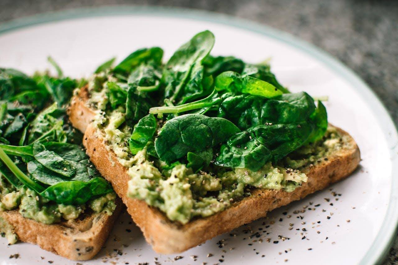 Toast with avocado and spinach leaves.