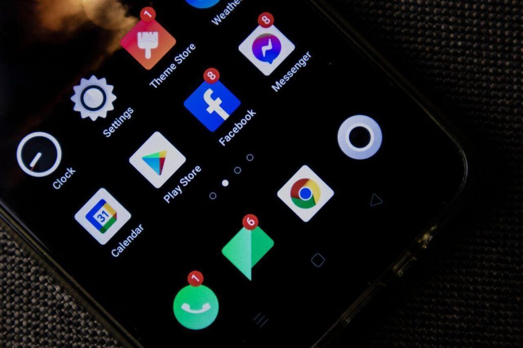 a close-up of a smartphone screen displaying various social media and app icons with notifications